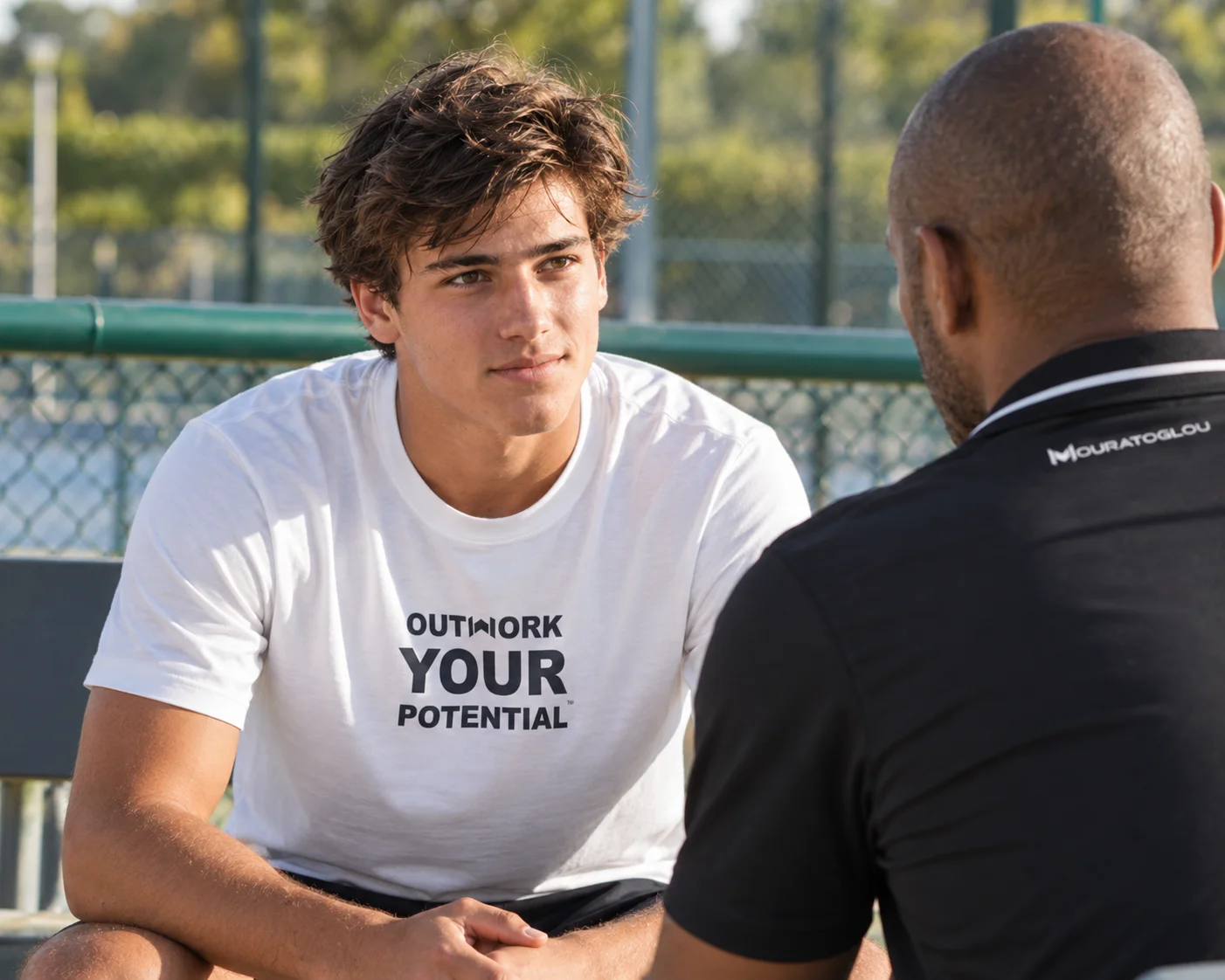Player wearing a white “Outwork your potential” Mouratoglou T-shirt