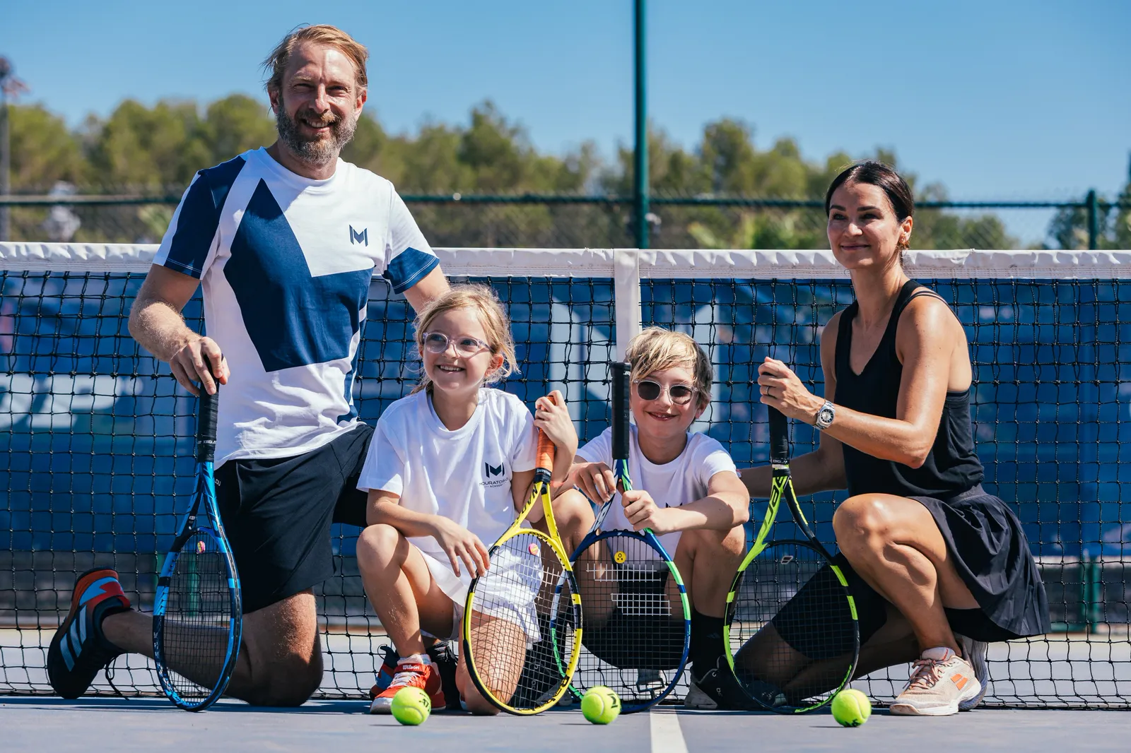 Familia jugando al tenis con un entrenador en la pista