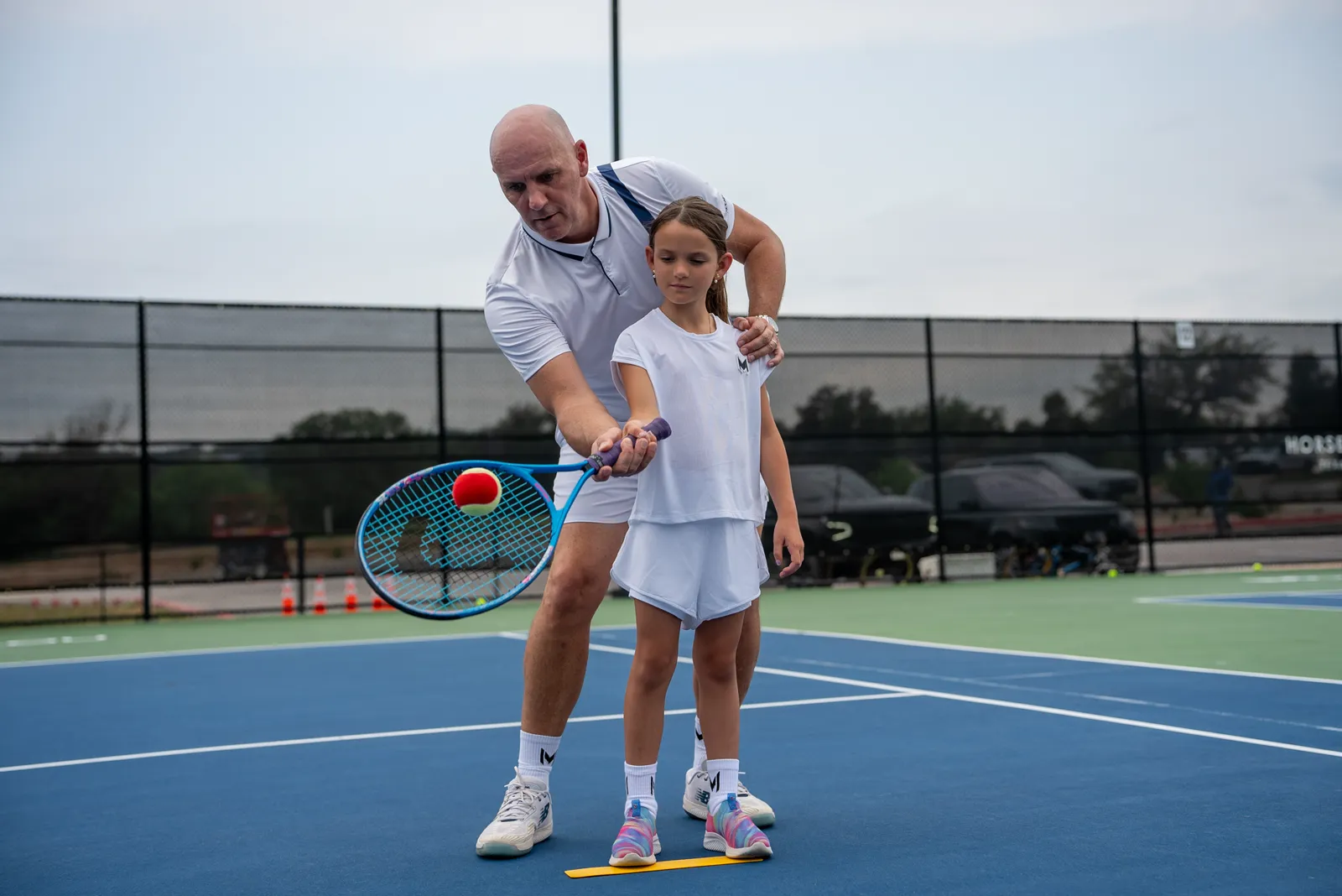 Young player hitting a red ball during a mini tennis lesson
