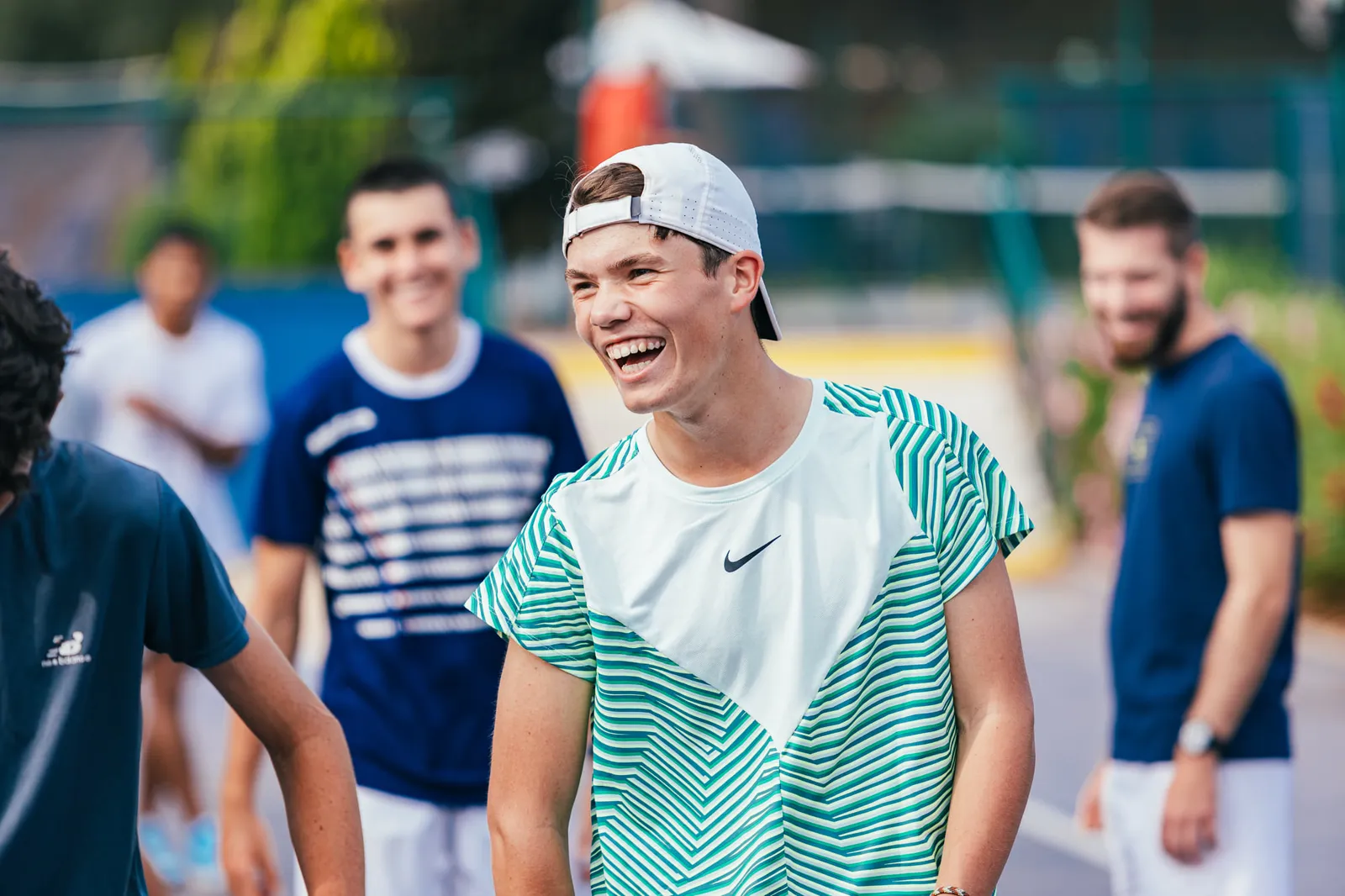 Jeune joueur de tennis riant avec ses partenaires pendant un entraînement