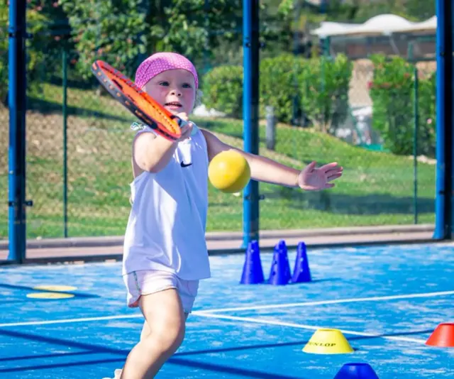 Niño sosteniendo una pelota de tenis de espuma en la pista