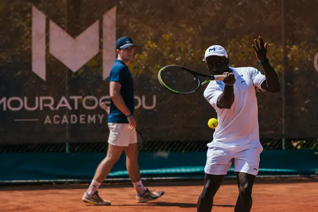 Adult player hitting a high volley at the net on a clay court