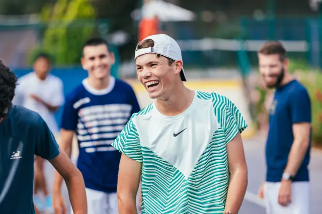 Jeune joueur de tennis riant avec ses partenaires pendant un entraînement