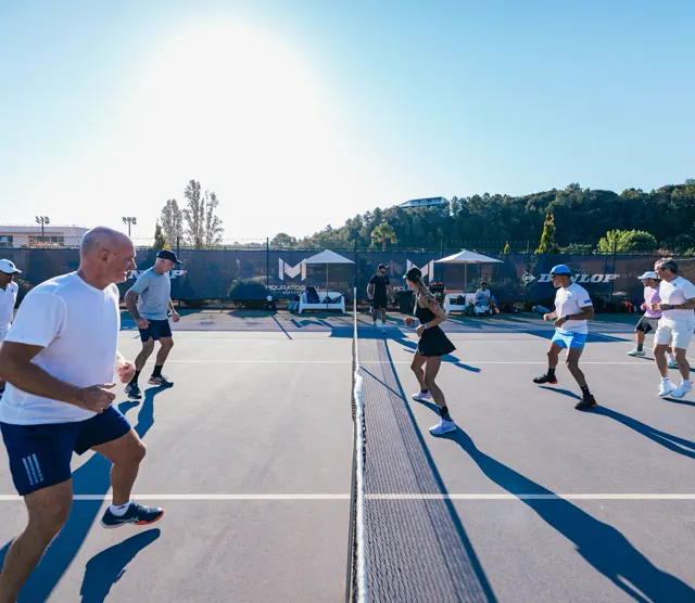 Adult players side-stepping along the net during a warm-up