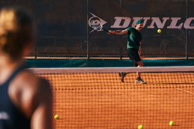 Player preparing a one-handed backhand, free hand supporting the racquet