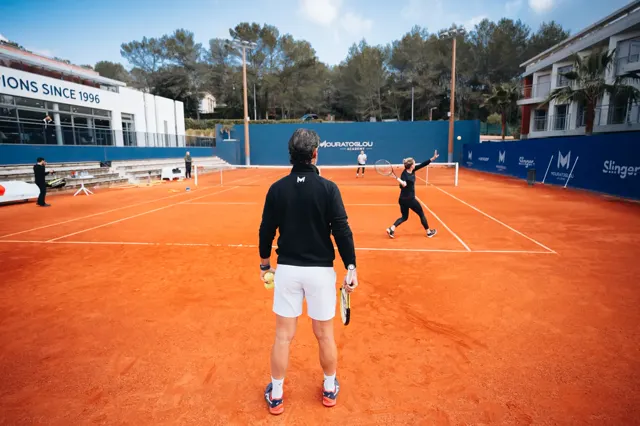 Coach watching a baseline rally on a clay court at the Mouratoglou Academy