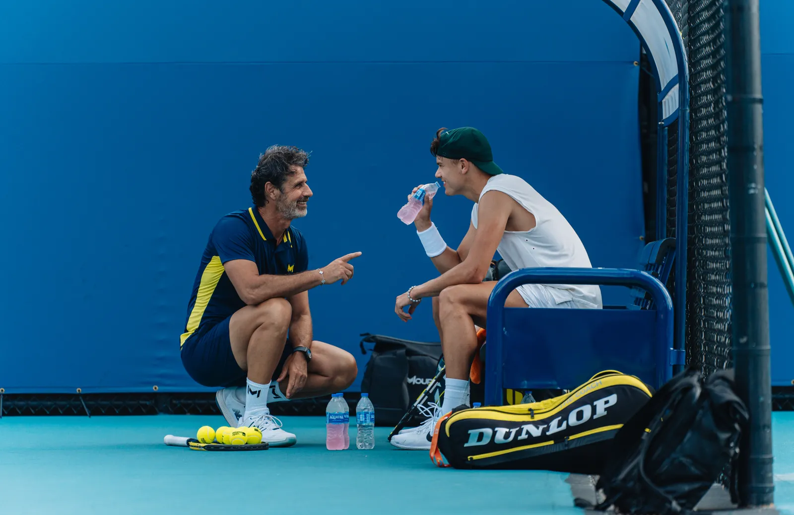 Coach échangeant avec un joueur sur un court de tennis