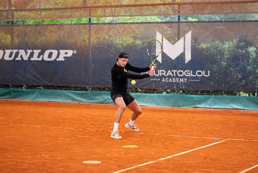 Player hitting the ball on a clay court at the Mouratoglou Academy
