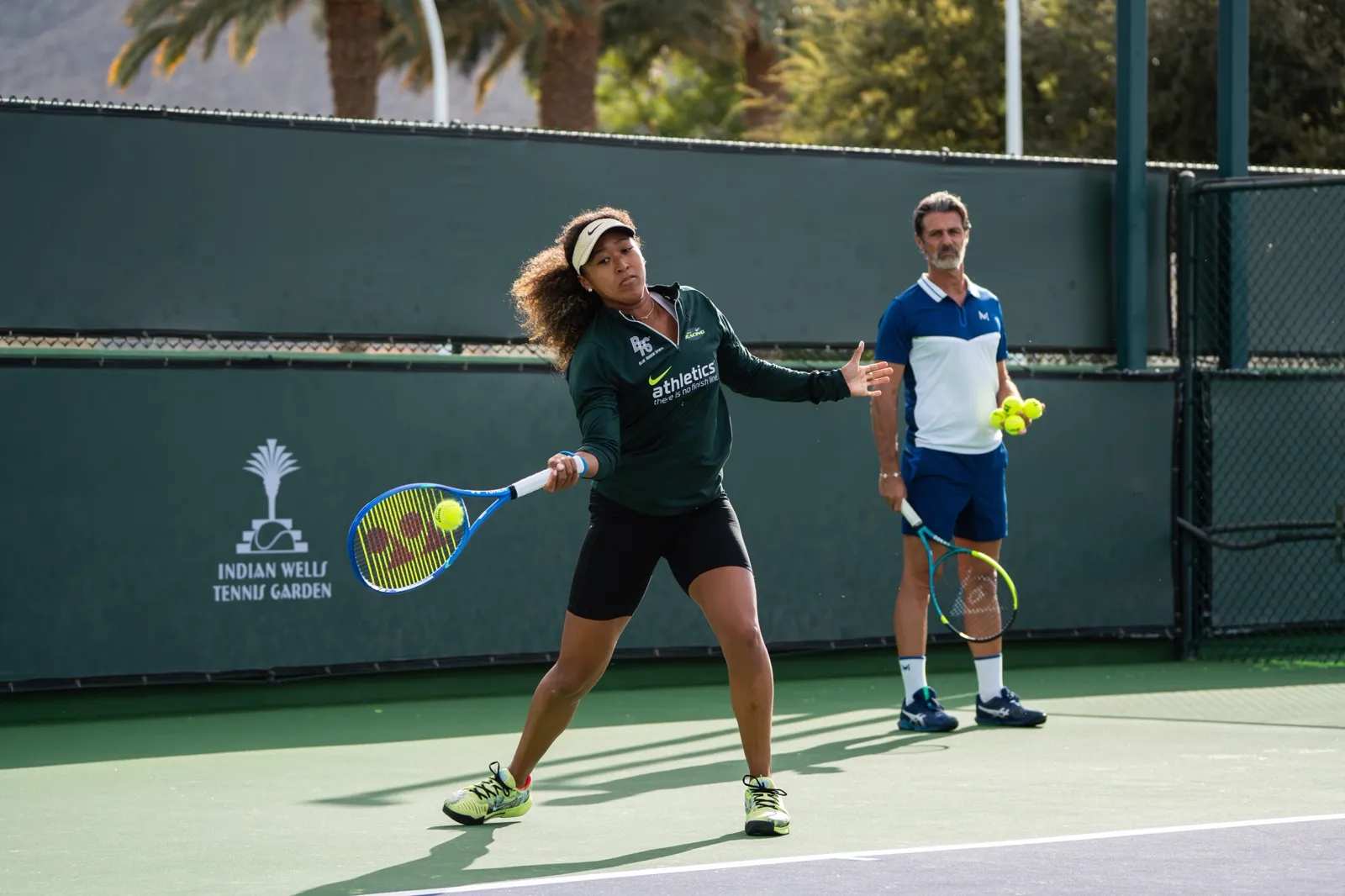 Joueuse et coach échangeant des balles lors d’un entraînement sur court dur