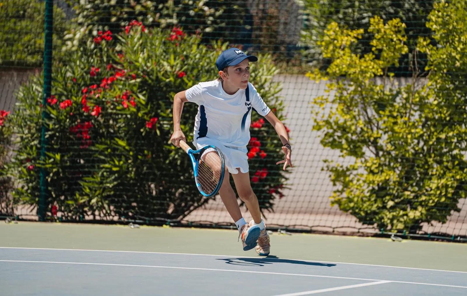 Jeune joueur qui sprinte sur le court pour rattraper une balle à l’entraînement