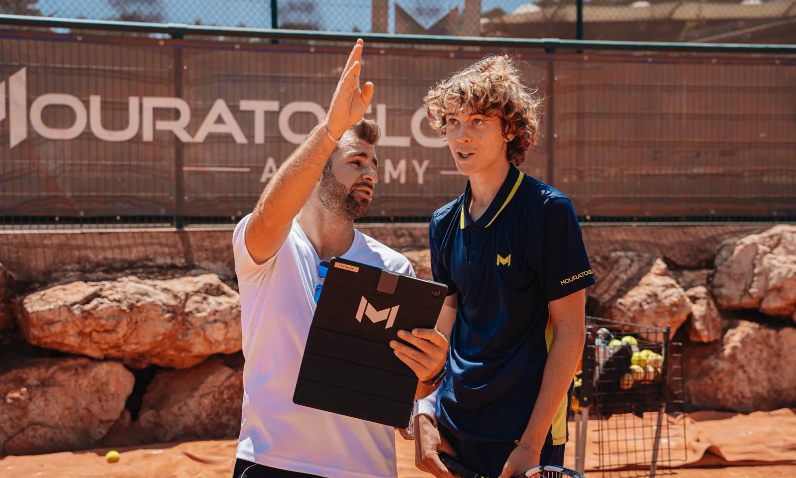 Coach de la Mouratoglou Academy montrant une trajectoire haute à un jeune joueur