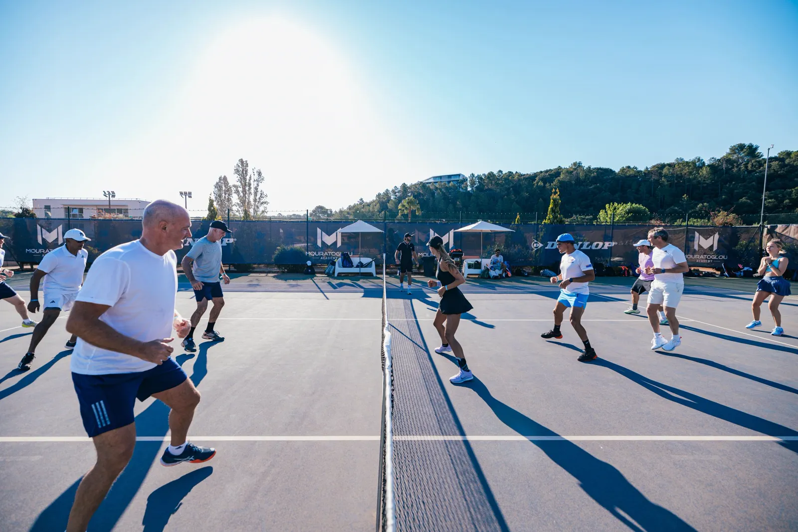 Groupe de joueurs faisant un exercice de préparation physique sur un court extérieur