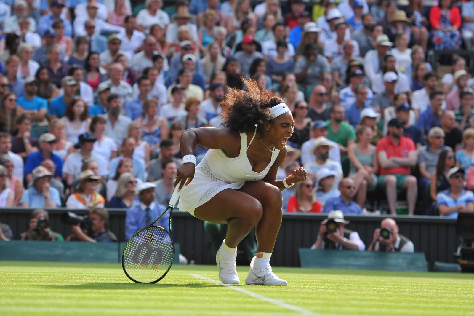 Match de tennis sur un court en gazon devant des tribunes pleines