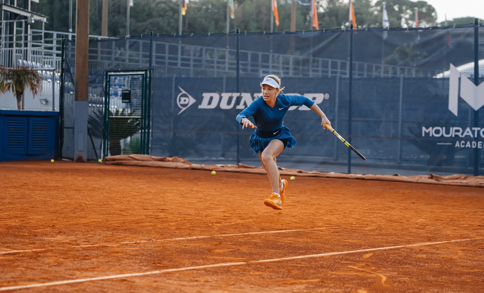 Spieler läuft auf einem Sandplatz Richtung Netz