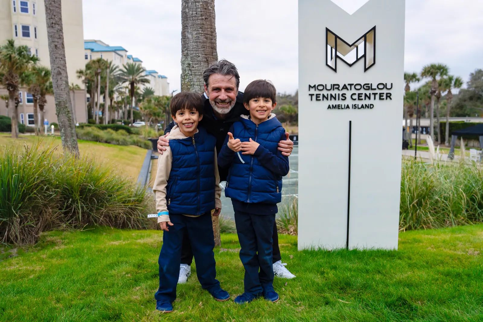 Patrick Mouratoglou in posa con due bambini davanti al totem Mouratoglou ad Amelia Island