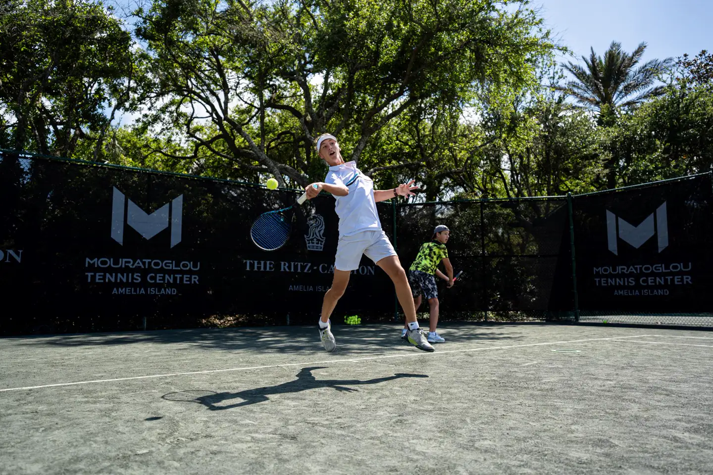 Joven jugador ejecutando un golpe potente en las pistas del Mouratoglou Tennis Center Amelia Island