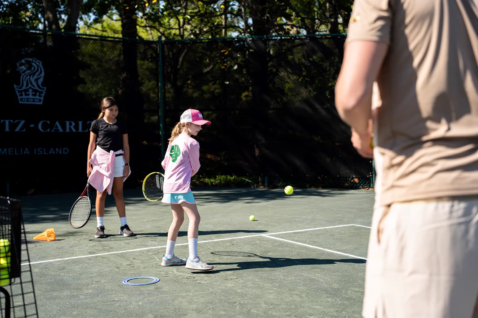 Niño esperando para devolver una pelota bajo la supervisión de un entrenador en el Mouratoglou Tennis Center Amelia Island