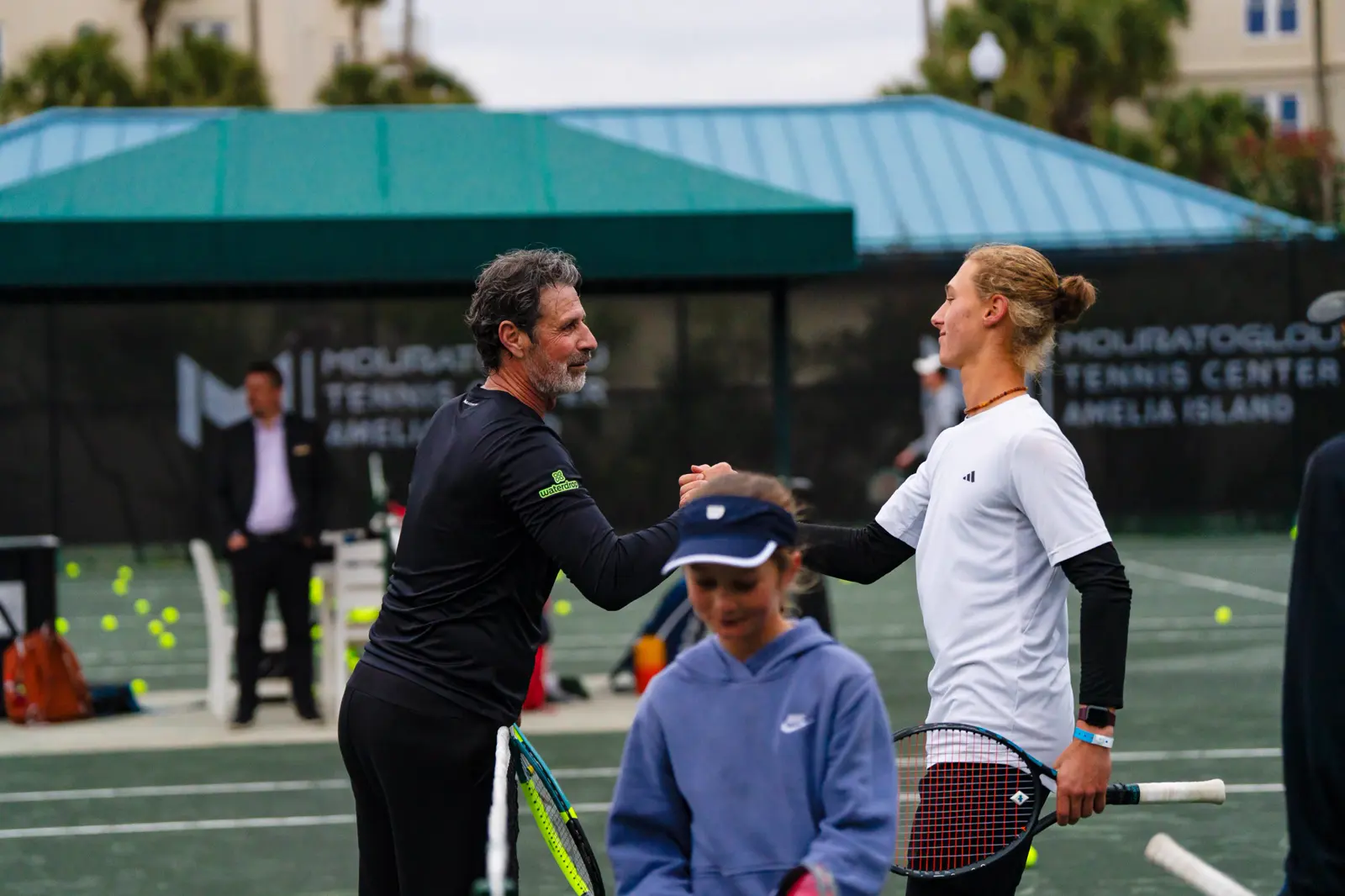 Patrick Mouratoglou chocando el puño con un jugador del programa junior en el Mouratoglou Tennis Center Amelia Island