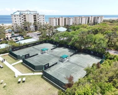 Tres pistas del Mouratoglou Tennis Center rodeadas de palmeras y sol