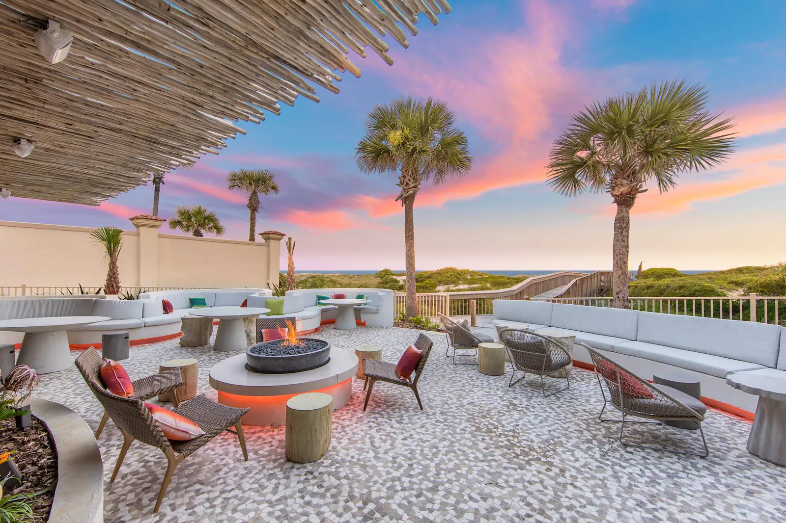 Terraza exterior con hoguera y palmeras al atardecer en The Ritz-Carlton, Amelia Island.