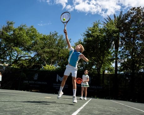 Niño saltando para golpear una pelota de tenis en las pistas del Mouratoglou Tennis Center Amelia Island