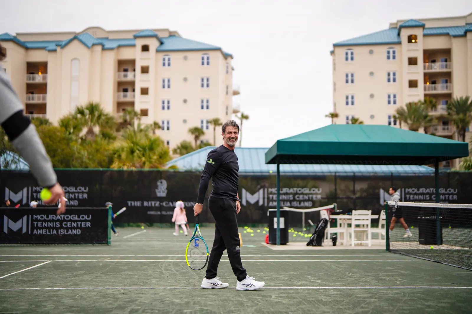 Patrick Mouratoglou cruzando la pista de tenis en el Mouratoglou Tennis Center Amelia Island
