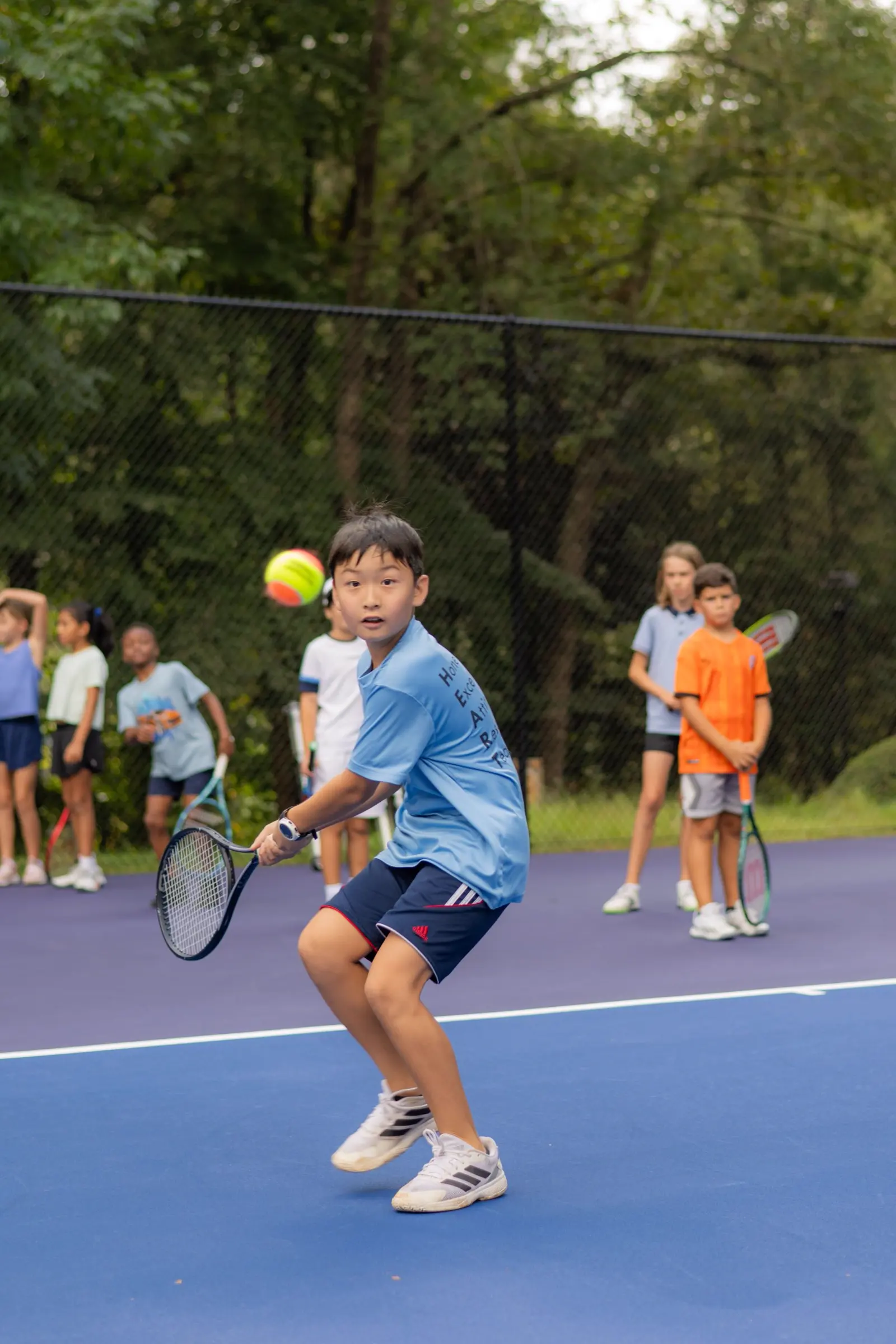 Un niño jugando al tenis en una pista exterior de la Mouratoglou Academy Atlanta