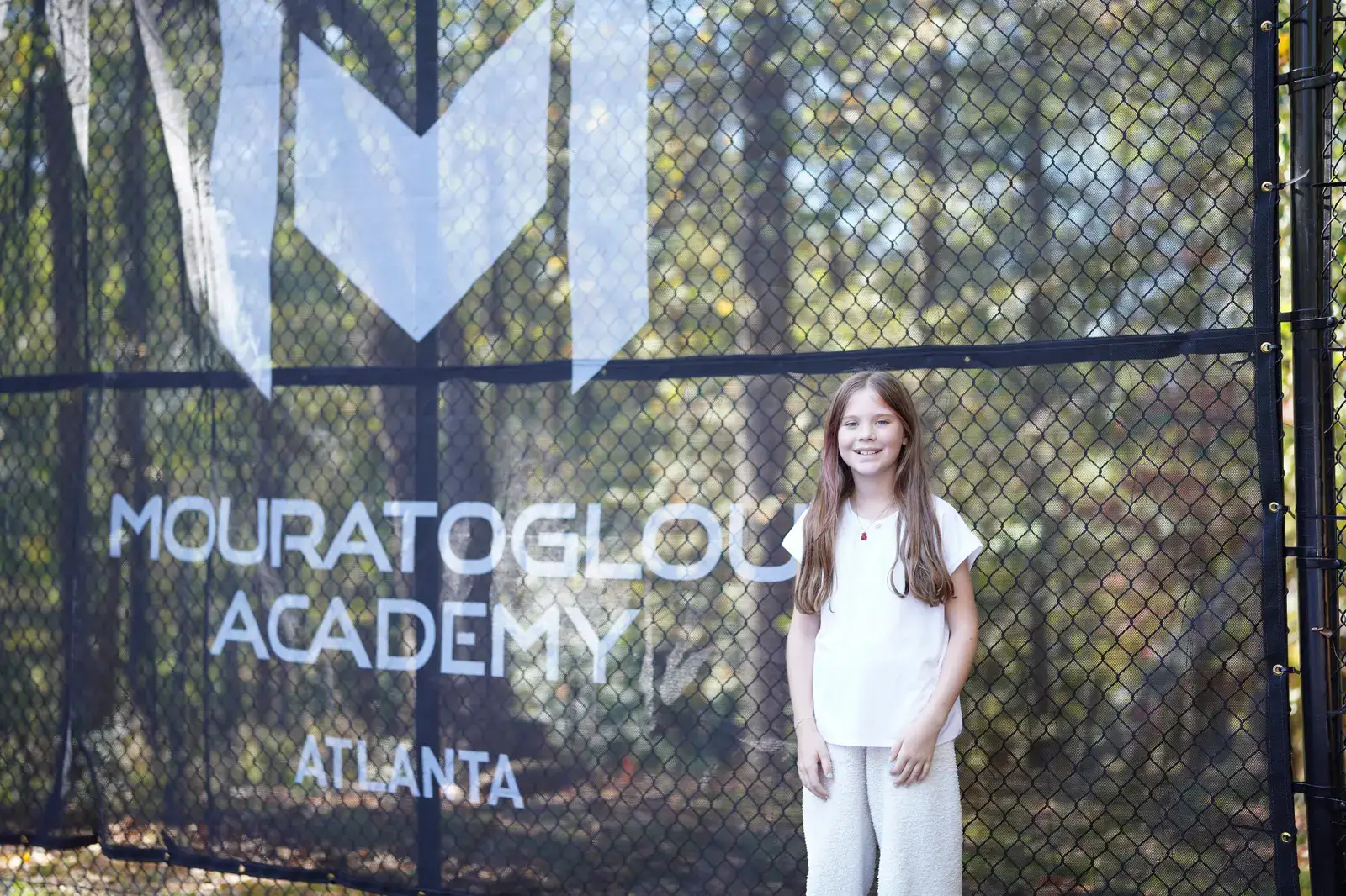 Joven jugadora de tenis delante de los cortavientos Mouratoglou en la Mouratoglou Academy Atlanta