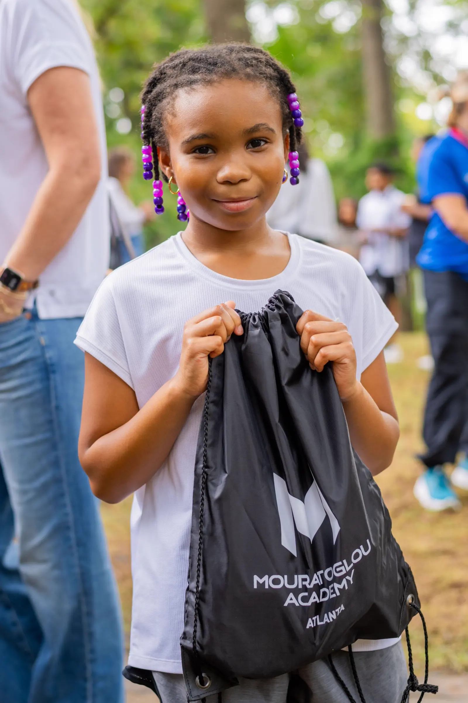 Una niña sonriente con una bolsa Mouratoglou en la Mouratoglou Academy Atlanta