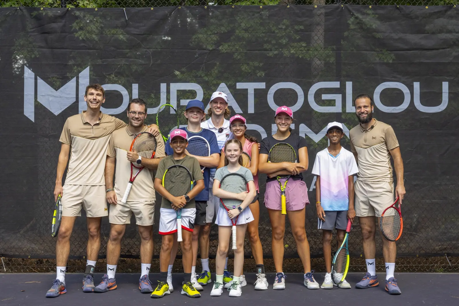Jugadores junior posando con sus entrenadores en las pistas de la Mouratoglou Academy Atlanta