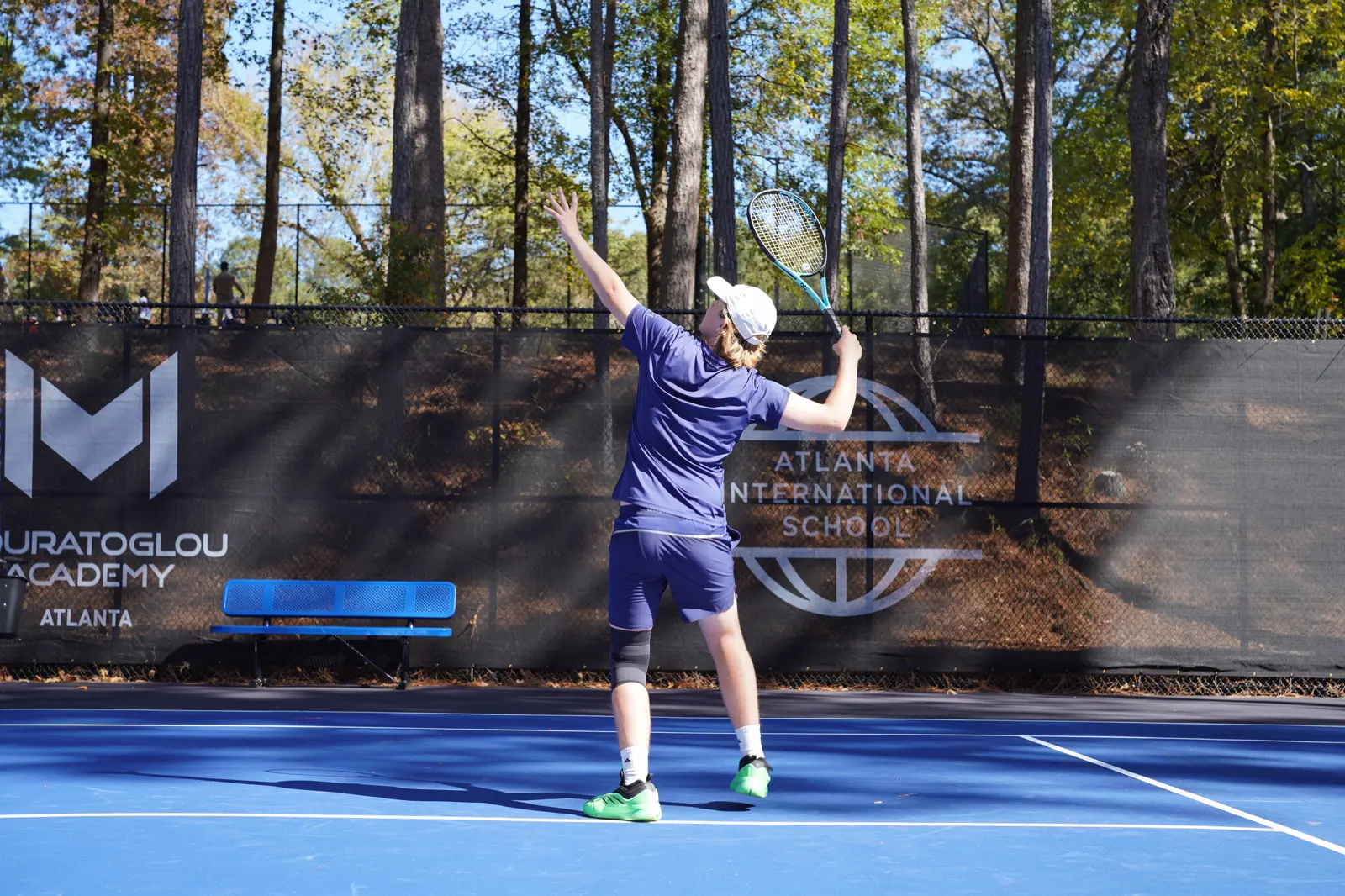Junger Spieler beim Aufschlag auf einem blauen Hartplatz an der Mouratoglou Academy Atlanta.