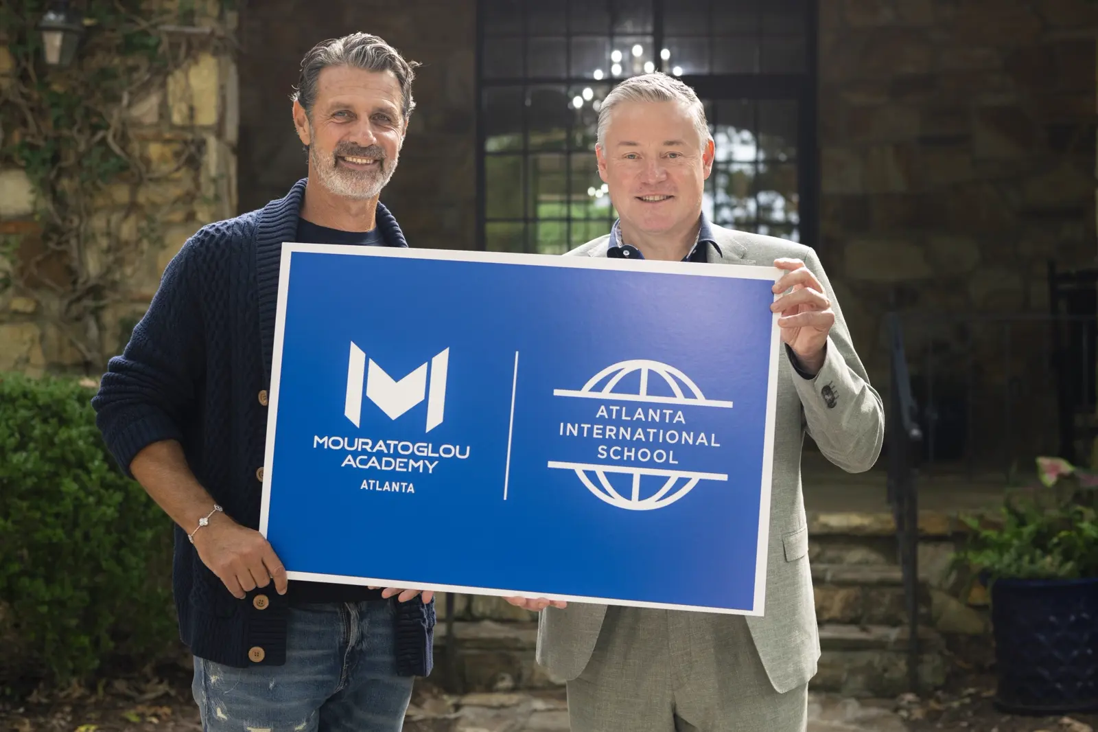 Patrick Mouratoglou e un partner reggono un cartello Mouratoglou Academy Atlanta e Atlanta International School