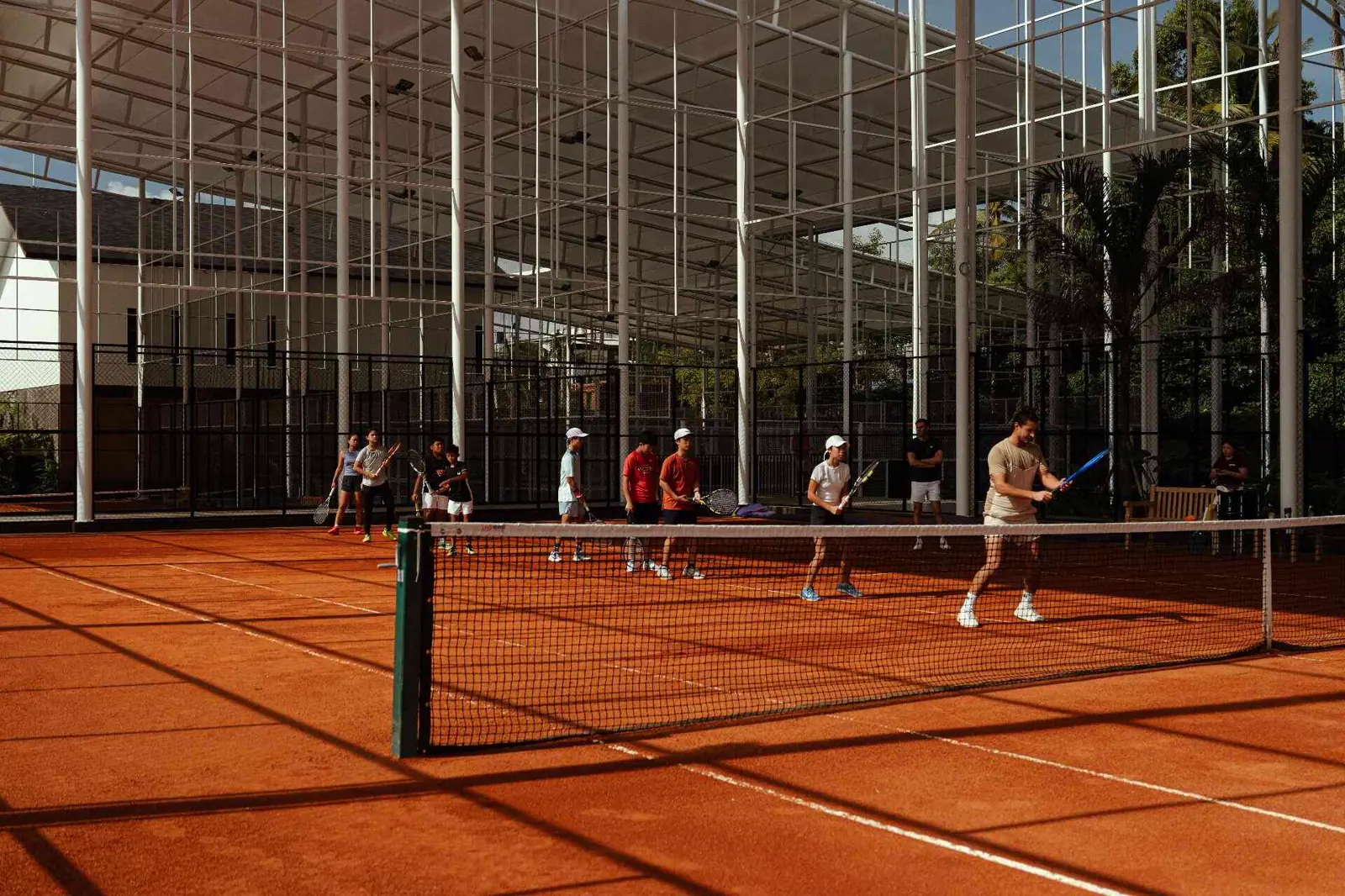 Giovani giocatori in una sessione di gruppo sui campi in terra battuta semi-coperti del Mouratoglou Tennis Center Bali
