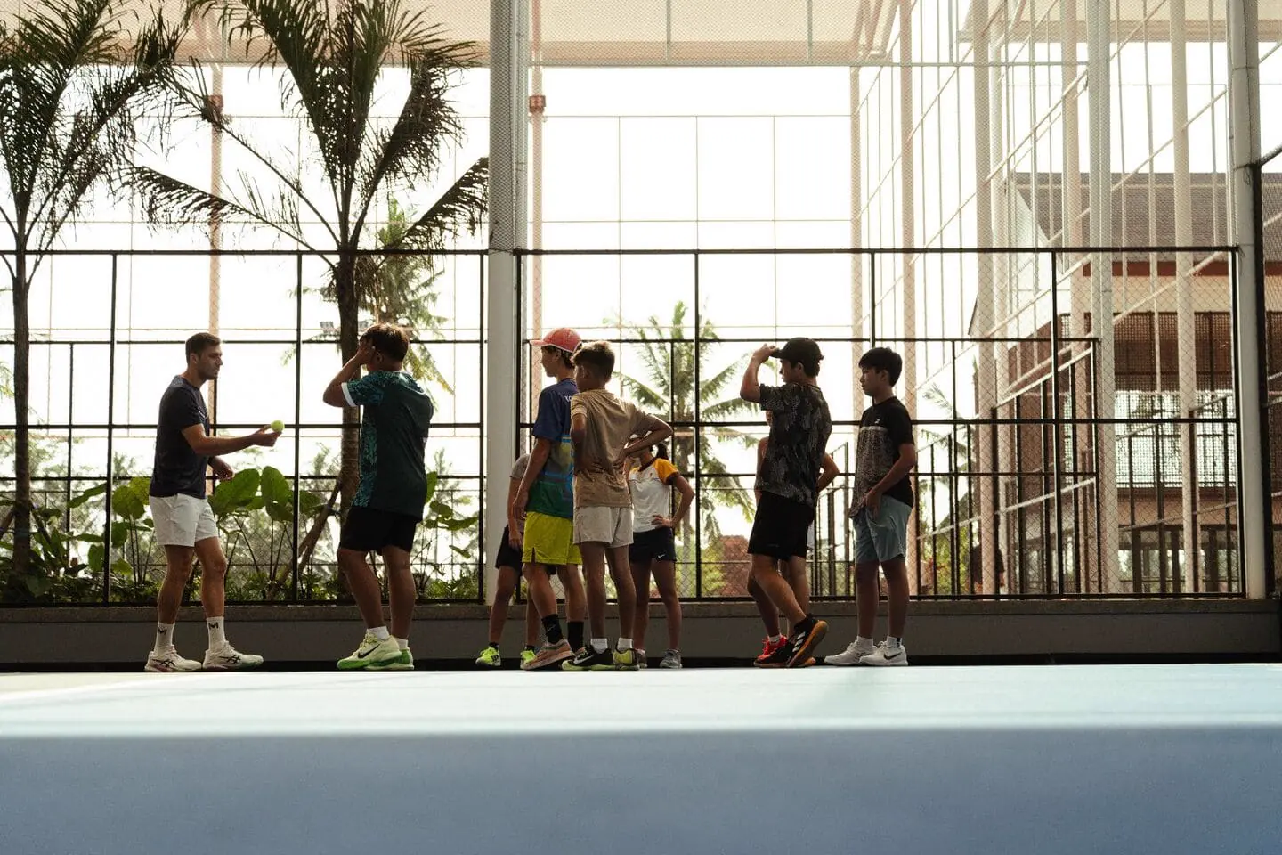 Coach dà istruzioni a giovani giocatori durante un camp al Mouratoglou Tennis Center Bali