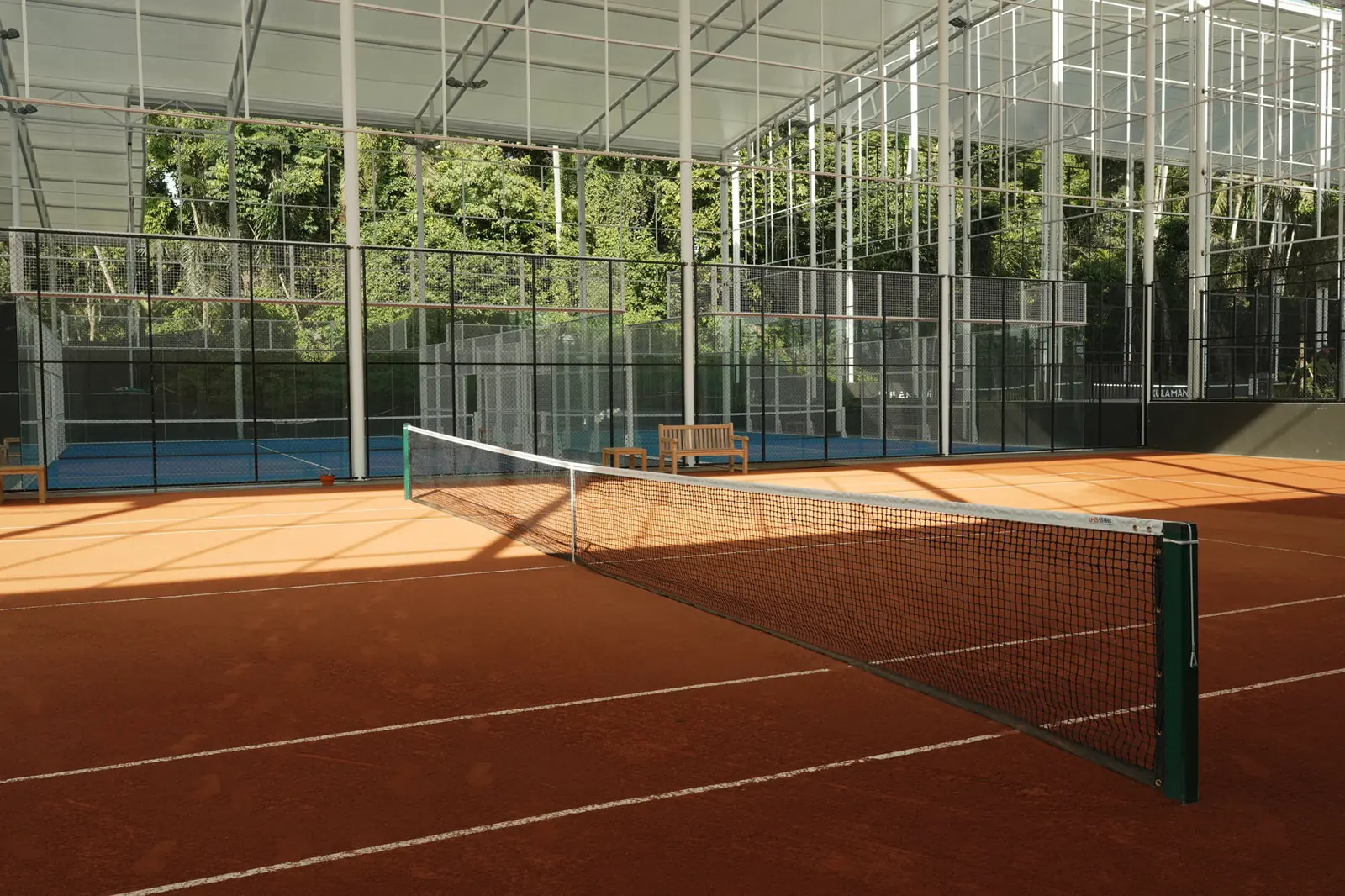 Court de tennis en terre battue semi-couvert entouré d’un décor tropical au Mouratoglou Tennis Center Bali