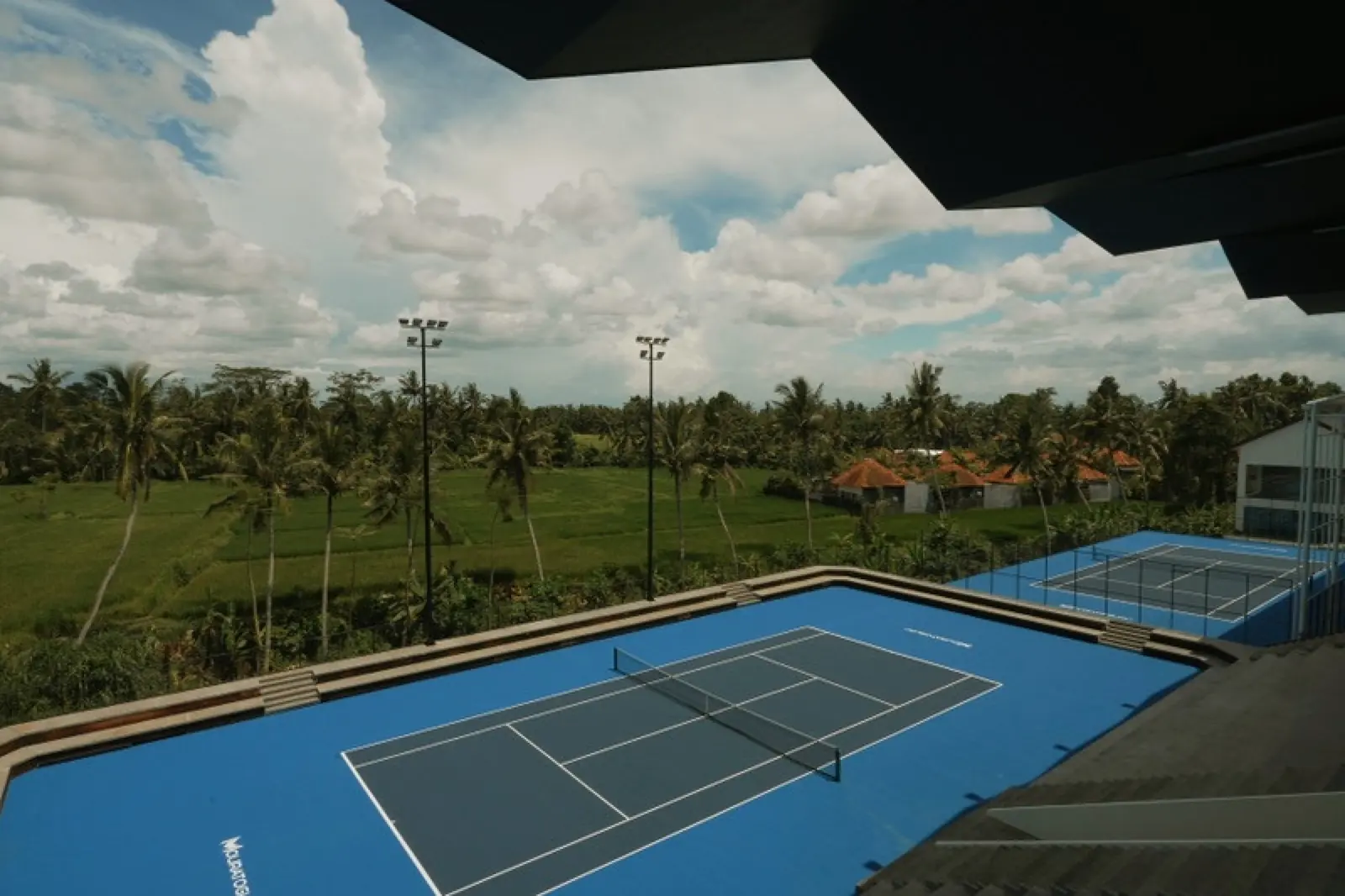 Court extérieur en dur avec tribune couverte et un second court au Mouratoglou Tennis Center Bali