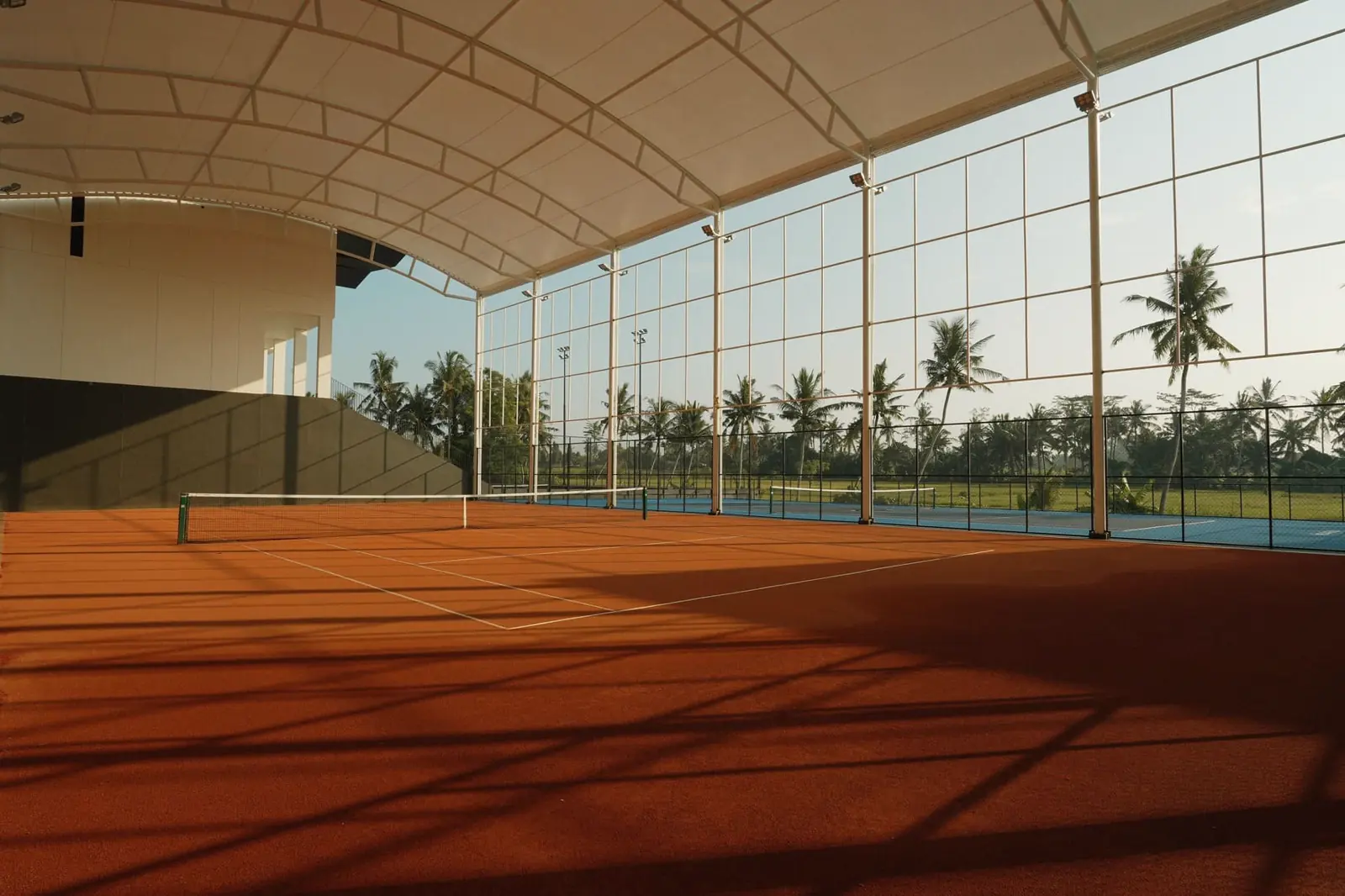 Court de tennis en terre battue semi-couvert entouré d’un décor tropical à Bali
