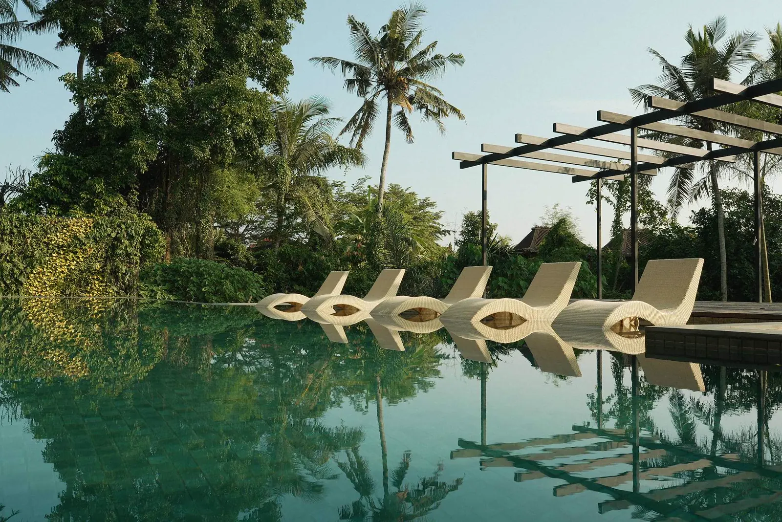 Piscina a sfioro e lettini tra la vegetazione tropicale al Kula Mani, Bali.