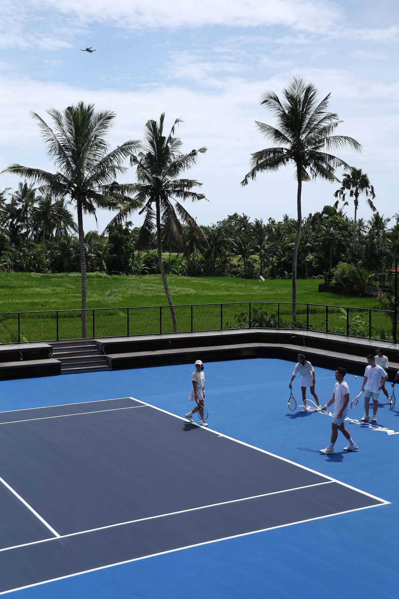 Giocatori che si allenano su un campo da tennis affacciato sulle risaie di Bali.