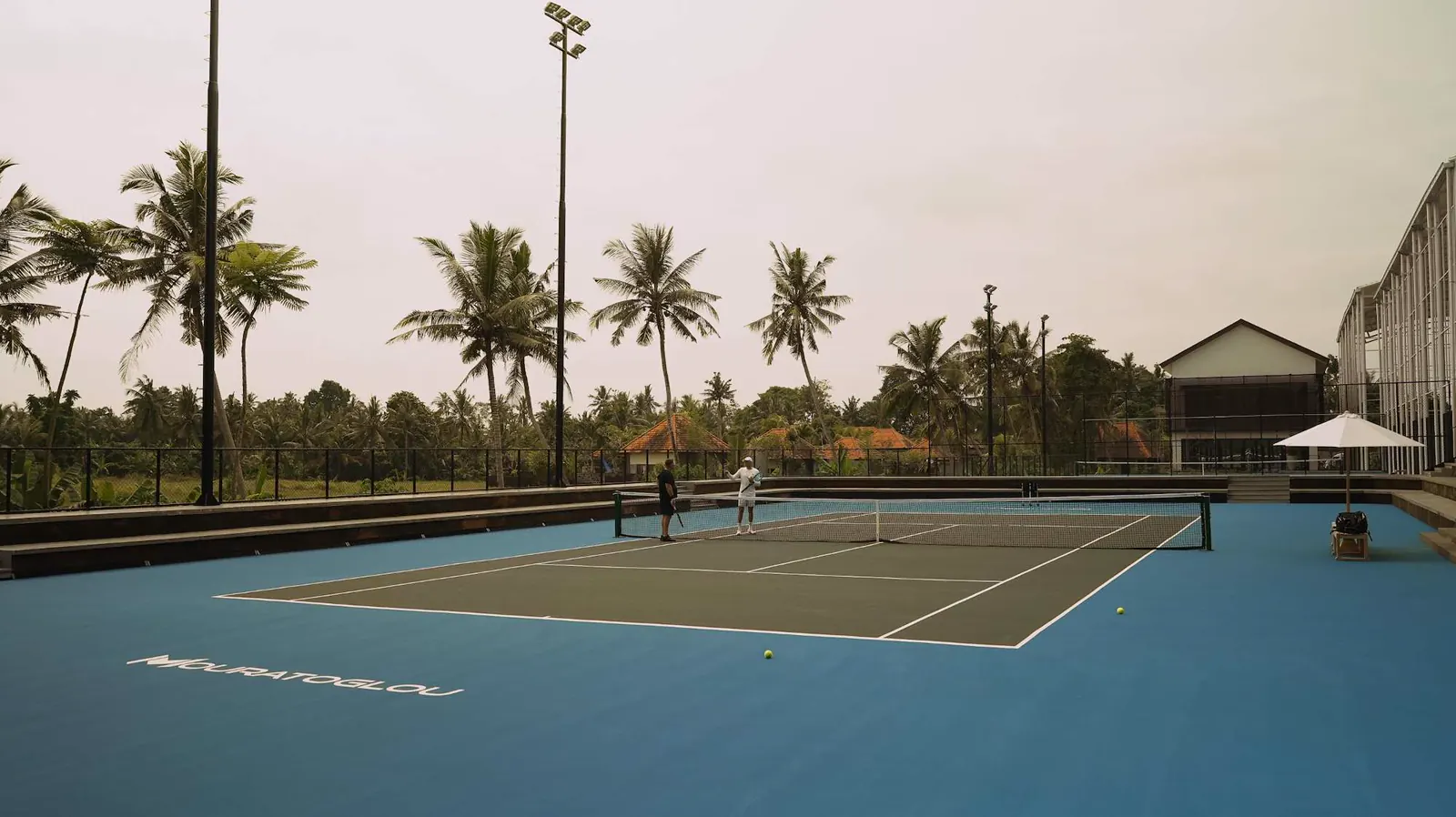 Campi da tennis e palme sotto un tenue cielo serale al Kula Mani, Bali.