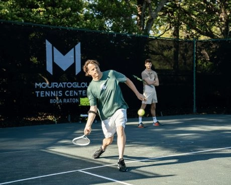 Coach gibt einem Spieler eine private Tennisstunde auf einem Außenplatz im Mouratoglou Tennis Center Boca Raton.