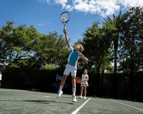 Juniorspieler trainieren gemeinsam auf einem Außenplatz im Mouratoglou Tennis Center Boca Raton.