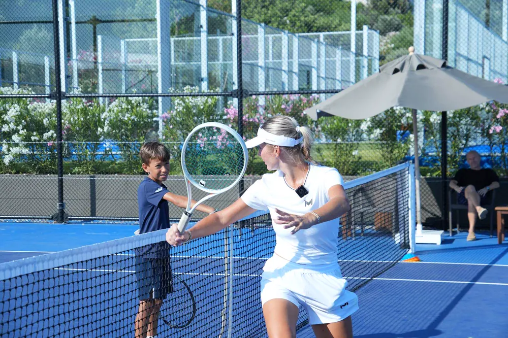 Entrenador Mouratoglou chocando la mano con un joven jugador durante una sesión de campamento junior en Bodrum.