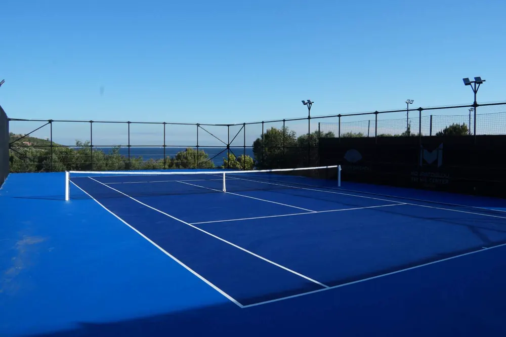 Pista de tenis azul vacía con vistas al mar Egeo en el Mouratoglou Tennis Center Bodrum.