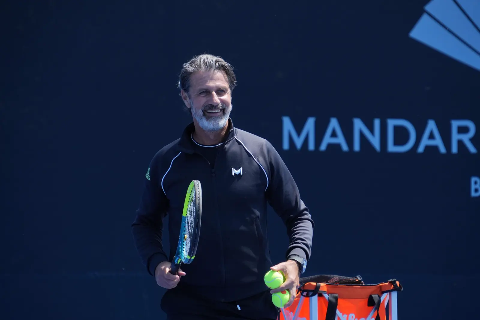 Patrick Mouratoglou tenant une raquette et des balles au Mouratoglou Tennis Center Bodrum