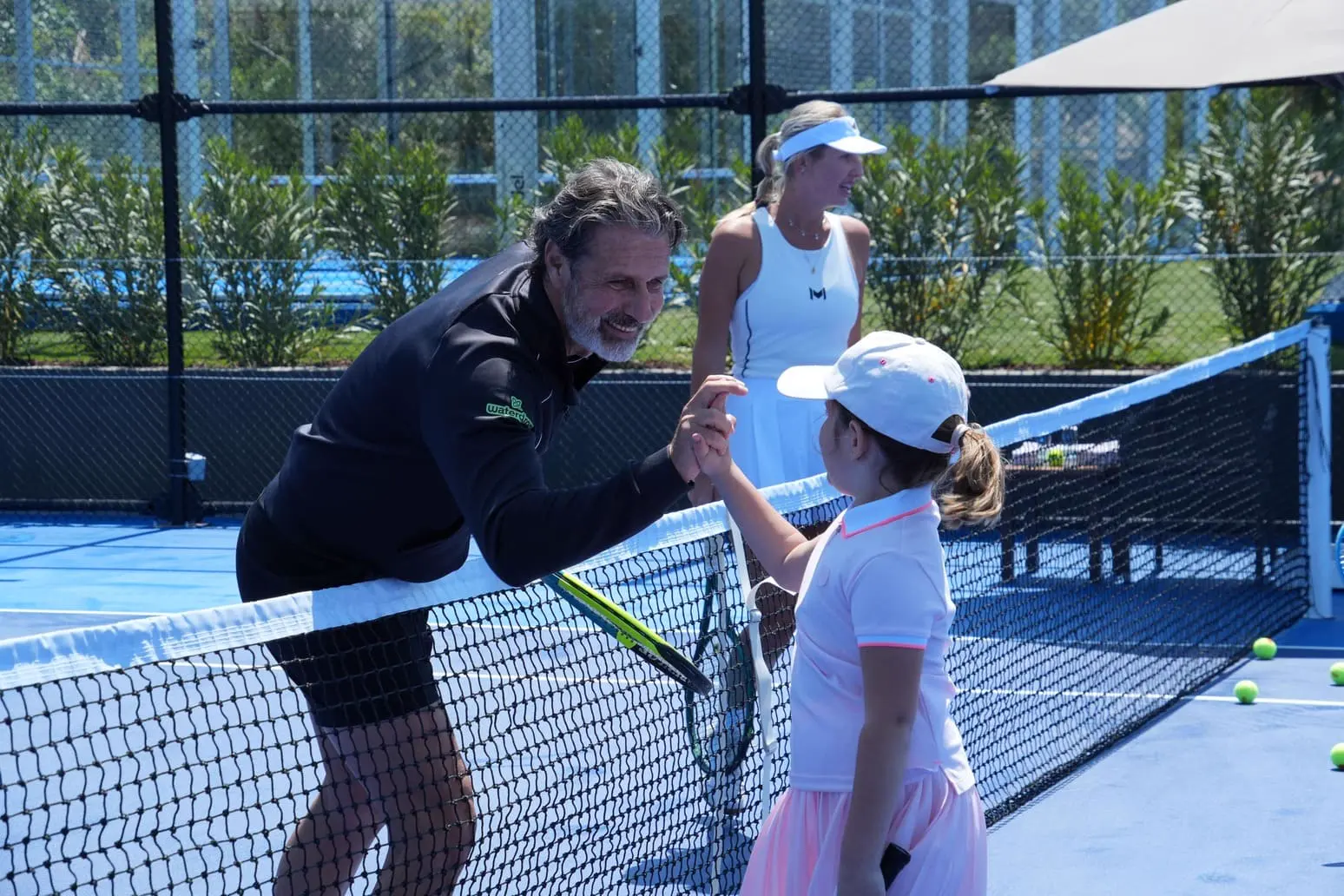 Patrick Mouratoglou giving a high five to a young player at the net in Bodrum