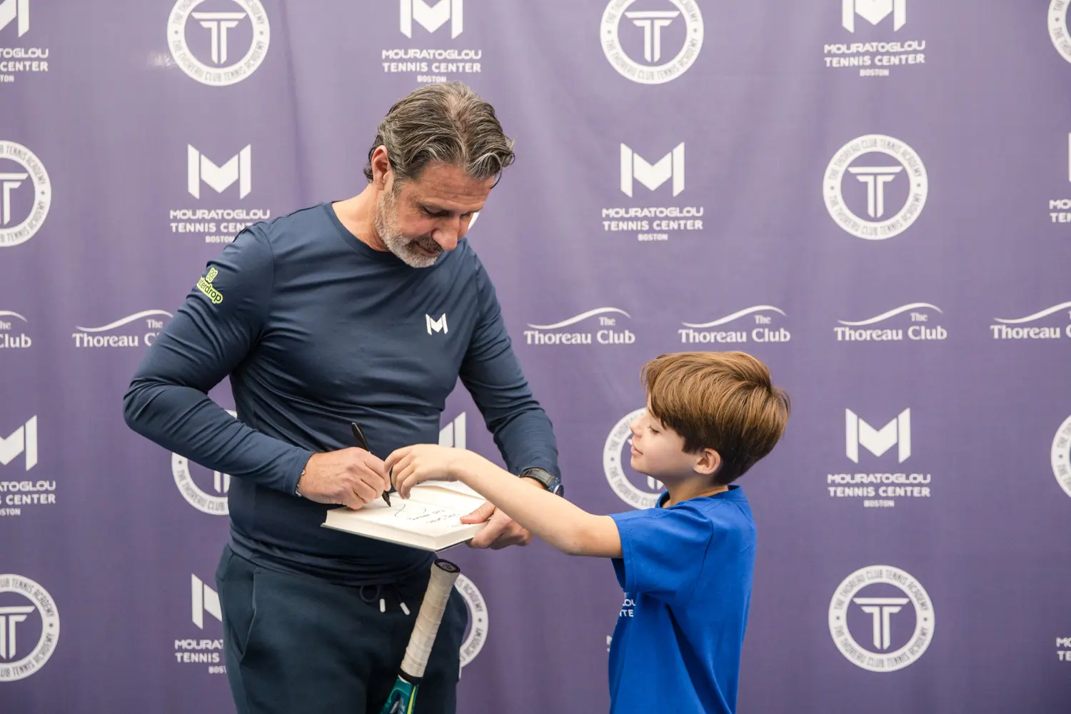 Patrick Mouratoglou firmando su libro a un joven jugador