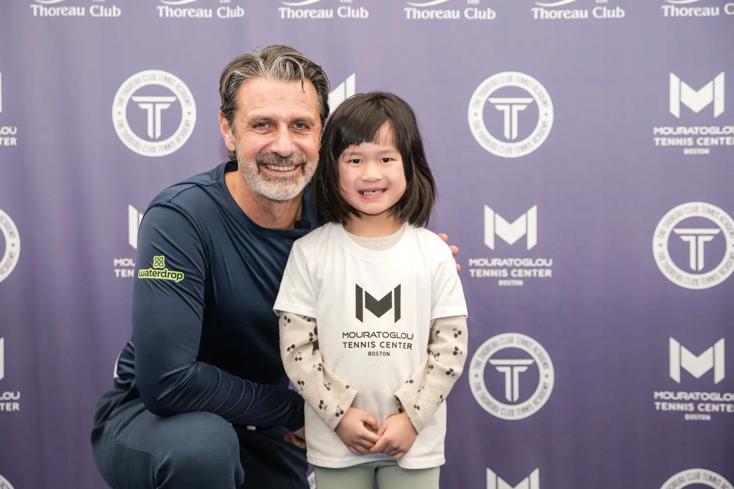 Patrick Mouratoglou sonriendo con un joven jugador en el Mouratoglou Tennis Center Boston