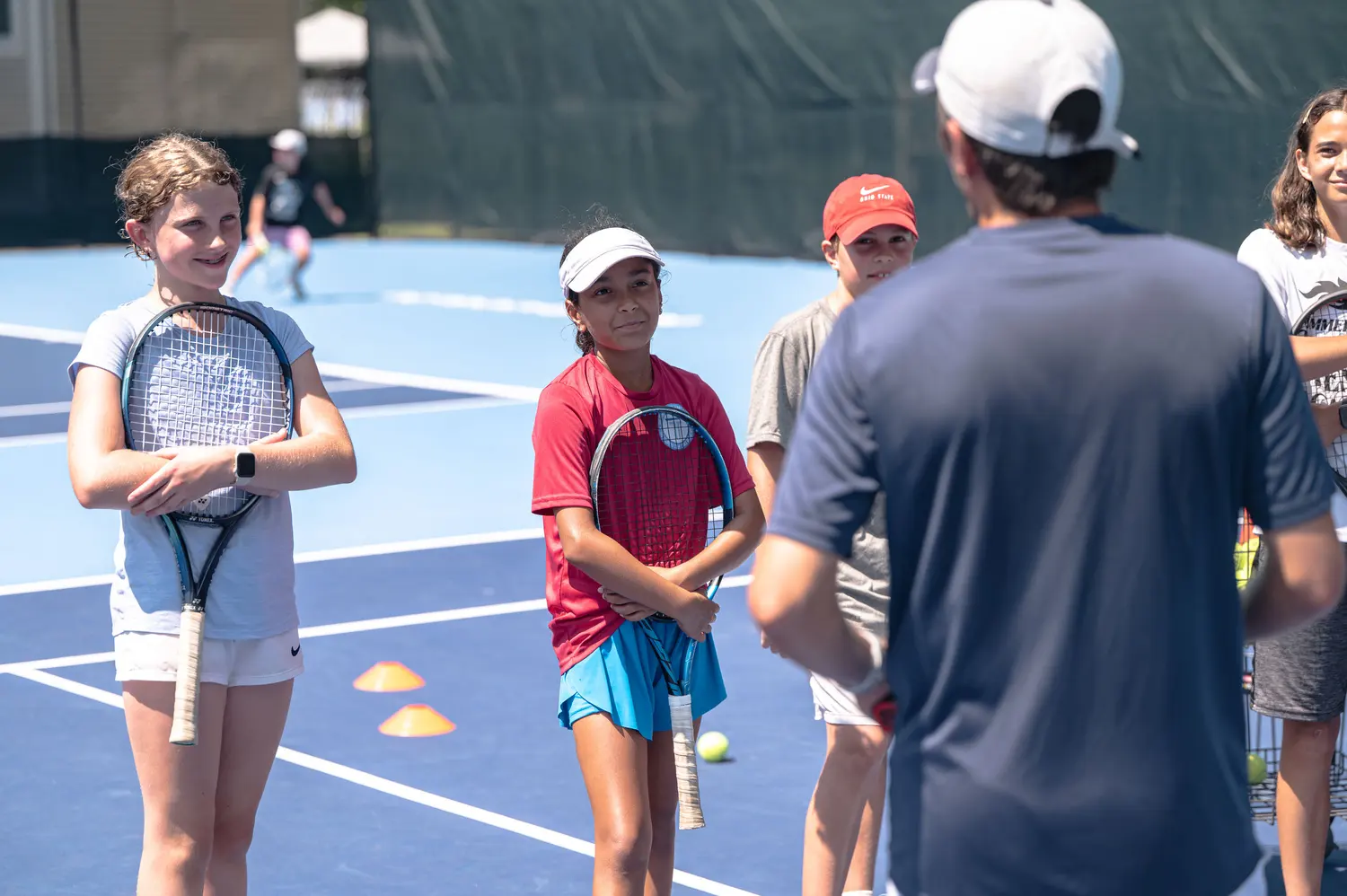 Bambini che ascoltano il loro coach durante un camp estivo al Mouratoglou Tennis Center Boston.
