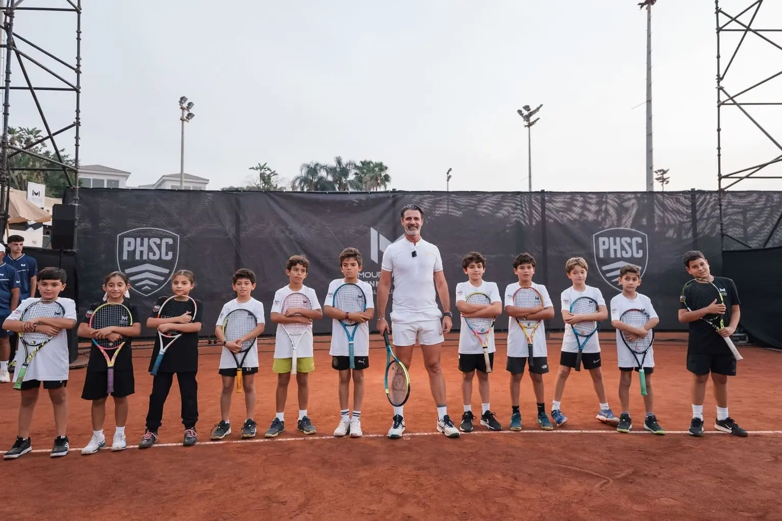 Patrick Mouratoglou avec un groupe de jeunes joueurs sur un court en terre battue à Palm Hills